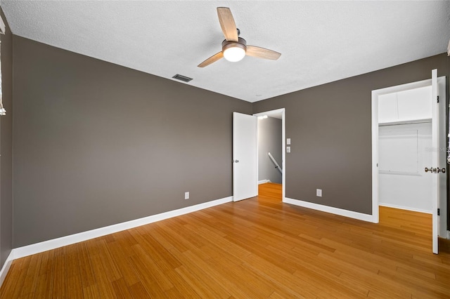 320 Tallahassee Dr NE, Saint Petersburg, FL 33702 - unfurnished bedroom with a walk in closet, light wood finished floors, baseboards, a closet, and a ceiling fan