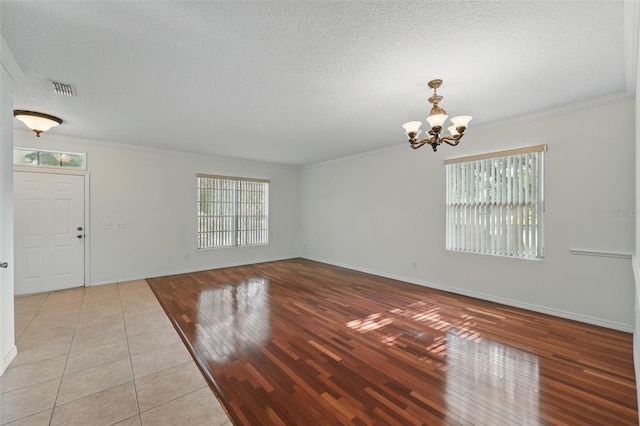 442 Graystone Blvd, Davenport, FL 33837 - empty room with healthy amount of natural light, a chandelier, crown molding, a textured ceiling, and baseboards