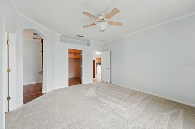 442 Graystone Blvd, Davenport, FL 33837 - unfurnished bedroom with light carpet, arched walkways, ornamental molding, a walk in closet, and baseboards