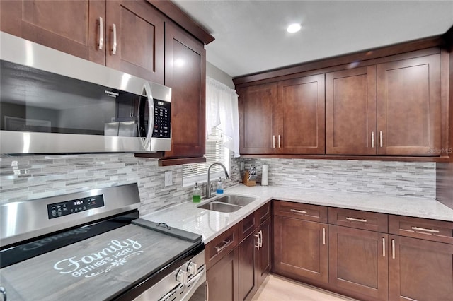 206 4th Ave NW, Ruskin, FL 33570 - kitchen with appliances with stainless steel finishes, a sink, light stone counters, and decorative backsplash