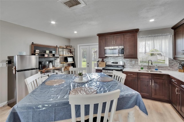 206 4th Ave NW, Ruskin, FL 33570 - kitchen with a sink, stainless steel appliances, tasteful backsplash, light wood-style flooring, and french doors
