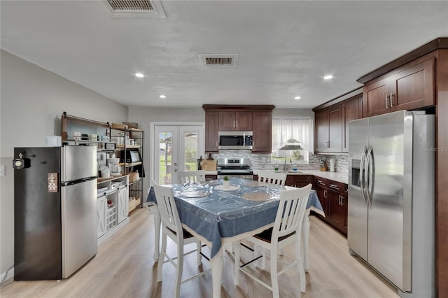 206 4th Ave NW, Ruskin, FL 33570 - kitchen featuring stainless steel appliances, light wood-type flooring, decorative backsplash, light countertops, and a sink
