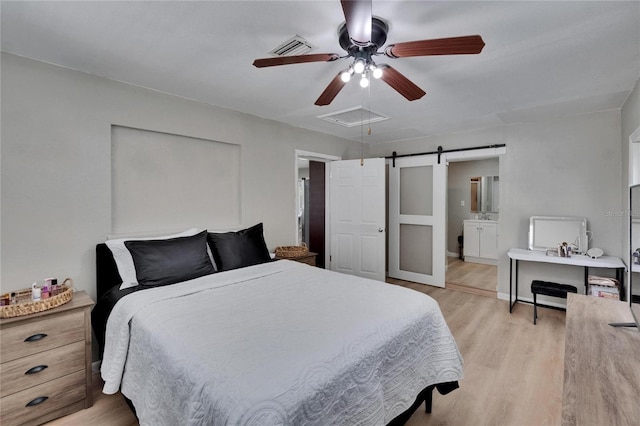 206 4th Ave NW, Ruskin, FL 33570 - bedroom with light wood-type flooring, a barn door, a ceiling fan, and ensuite bathroom