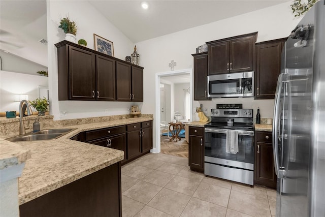 10197 Meadow Wren Ave, Weeki Wachee, FL 34613 - kitchen featuring stainless steel appliances, a sink, lofted ceiling, dark brown cabinets, and light tile patterned flooring