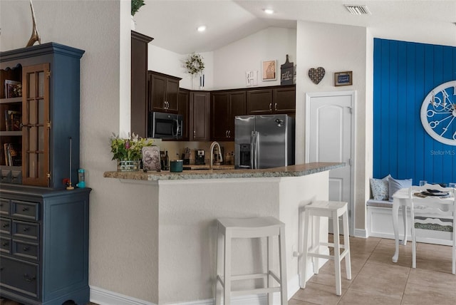 10197 Meadow Wren Ave, Weeki Wachee, FL 34613 - kitchen with appliances with stainless steel finishes, dark brown cabinetry, a kitchen breakfast bar, lofted ceiling, and a peninsula