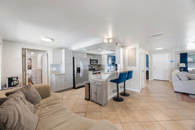 1706 Sloop Pl, Brandon, FL 33511 - kitchen with open floor plan, stainless steel appliances, a kitchen bar, light tile patterned floors, and a sink