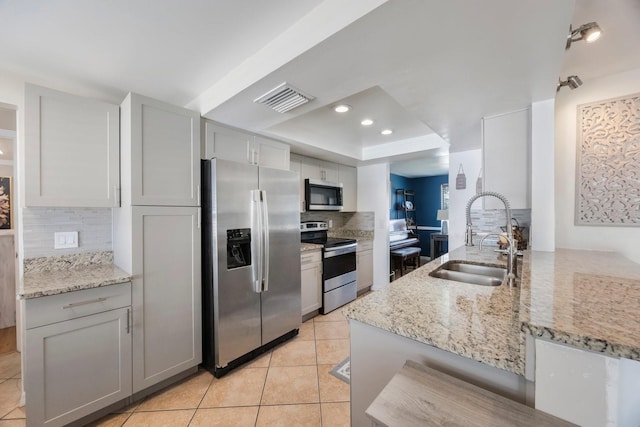 1706 Sloop Pl, Brandon, FL 33511 - kitchen featuring stainless steel appliances, a sink, a raised ceiling, decorative backsplash, and light tile patterned floors