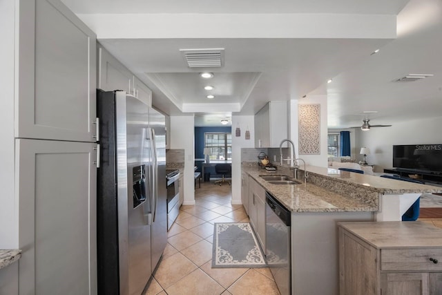 1706 Sloop Pl, Brandon, FL 33511 - kitchen featuring a sink, stainless steel appliances, a tray ceiling, open floor plan, and light stone countertops