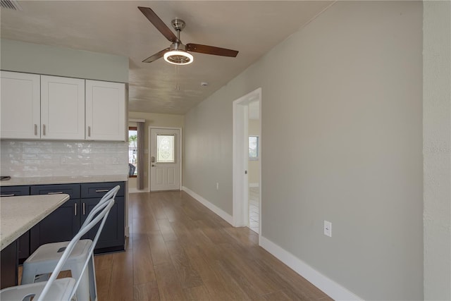 2010 Bayview Pl, Indian Rocks Beach, FL 33785 - kitchen with a ceiling fan, backsplash, white cabinetry, wood finished floors, and baseboards