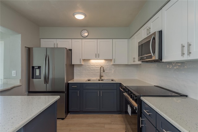 2010 Bayview Pl, Indian Rocks Beach, FL 33785 - kitchen with stainless steel appliances, a sink, white cabinetry, and light wood-style floors