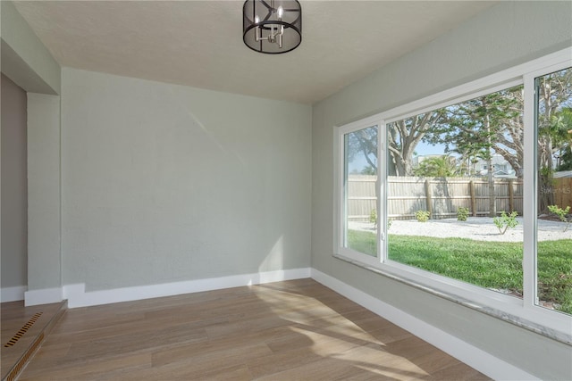 2010 Bayview Pl, Indian Rocks Beach, FL 33785 - unfurnished dining area with baseboards, wood finished floors, and a chandelier