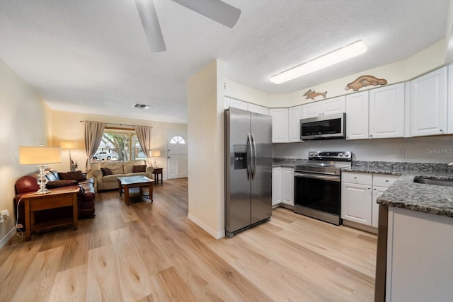 6282 41st Ave N, Saint Petersburg, FL 33709 - kitchen with stainless steel appliances, light wood finished floors, stone counters, open floor plan, and white cabinetry
