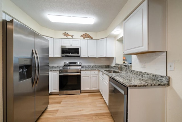 6282 41st Ave N, Saint Petersburg, FL 33709 - kitchen with appliances with stainless steel finishes, a sink, light wood-style flooring, white cabinetry, and a textured ceiling