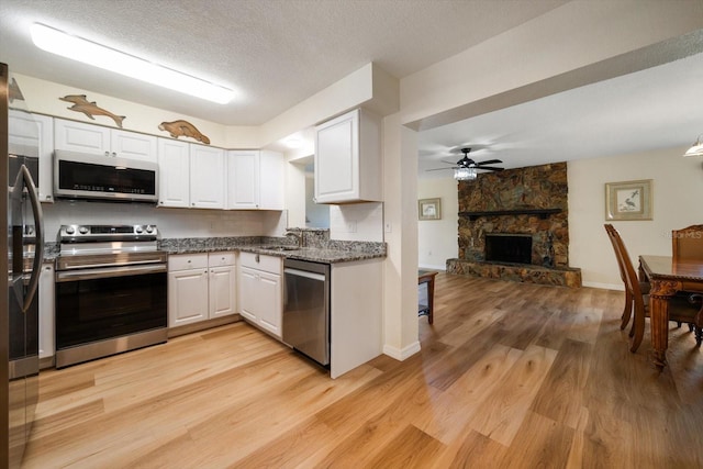 6282 41st Ave N, Saint Petersburg, FL 33709 - kitchen featuring appliances with stainless steel finishes, white cabinets, light wood-type flooring, a sink, and a textured ceiling