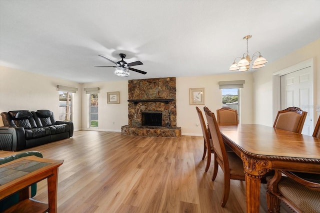 6282 41st Ave N, Saint Petersburg, FL 33709 - dining room featuring light wood finished floors, a chandelier, ceiling fan, a fireplace, and baseboards