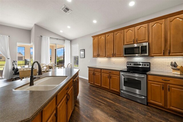 2350 126th Dr E, Parrish, FL 34219 - kitchen featuring stainless steel appliances, vaulted ceiling, dark countertops, dark wood-type flooring, and tasteful backsplash