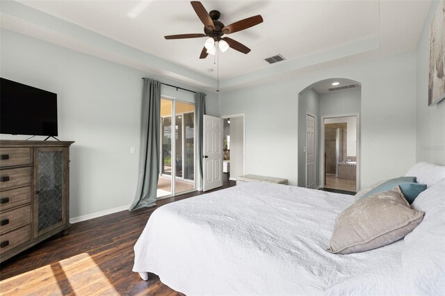 2350 126th Dr E, Parrish, FL 34219 - bedroom with arched walkways, access to exterior, dark wood-type flooring, a tray ceiling, and connected bathroom