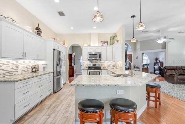 613 Sportsman Park Dr, Seffner, FL 33584 - kitchen with appliances with stainless steel finishes, a sink, arched walkways, light wood finished floors, and recessed lighting