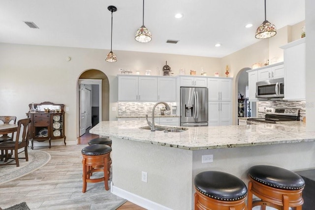613 Sportsman Park Dr, Seffner, FL 33584 - kitchen with appliances with stainless steel finishes, arched walkways, a sink, light wood-type flooring, and backsplash