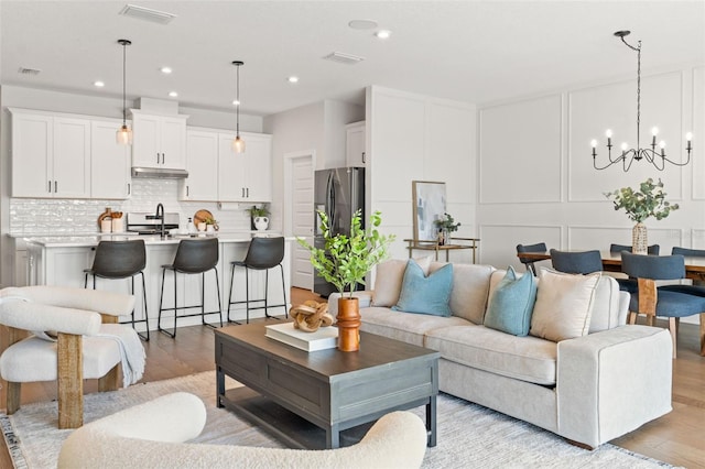 6123 Golden Nettle Dr, Apollo Beach, FL 33572 - living room featuring light wood-style floors, a chandelier, a decorative wall, and recessed lighting