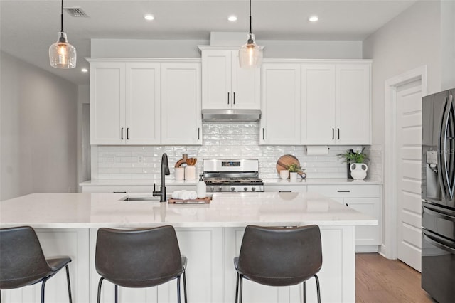 6123 Golden Nettle Dr, Apollo Beach, FL 33572 - kitchen with under cabinet range hood, stainless steel range with gas stovetop, fridge with ice dispenser, white cabinets, and a sink