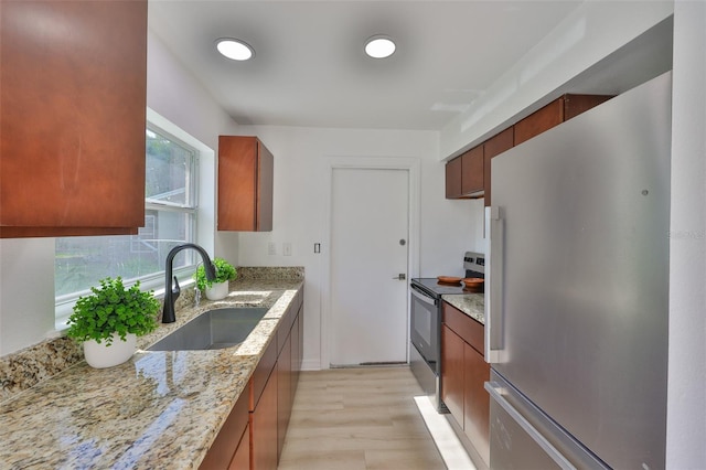 1110 Waterview Blvd E, Lakeland, FL 33801 - kitchen with stainless steel appliances, a sink, light wood finished floors, light stone counters, and brown cabinets
