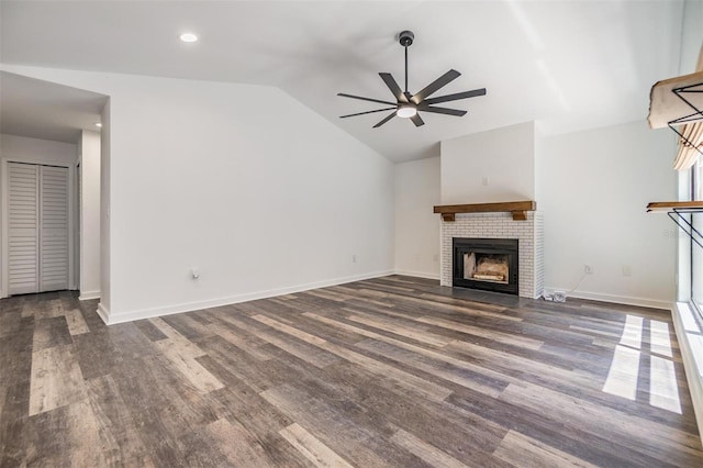660 Channing Dr, Palm Harbor, FL 34684 - unfurnished living room featuring ceiling fan, vaulted ceiling, wood finished floors, a tiled fireplace, and baseboards
