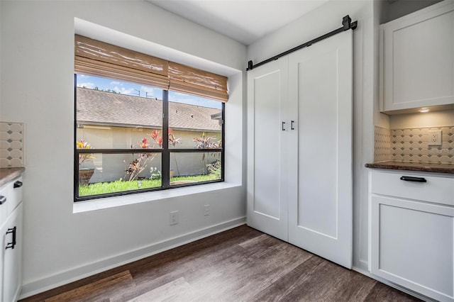 660 Channing Dr, Palm Harbor, FL 34684 - unfurnished bedroom with a barn door, dark wood finished floors, and baseboards