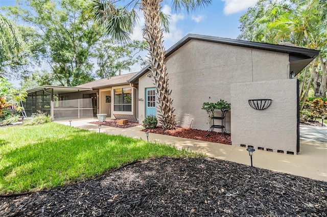 660 Channing Dr, Palm Harbor, FL 34684 - rear view of house with a sunroom, stucco siding, and a lawn