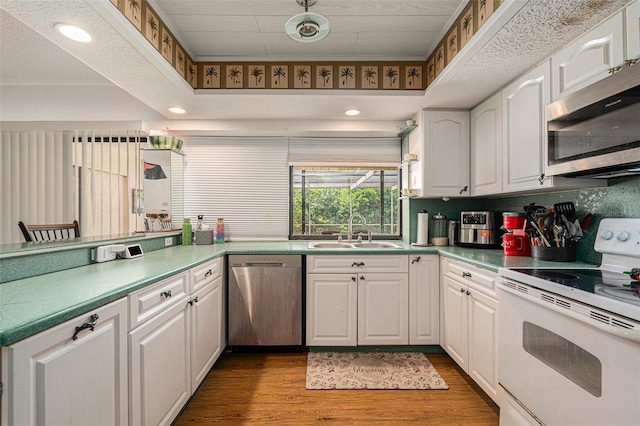 7700 Willow Brook Ct, Hudson, FL 34667 - kitchen with stainless steel appliances, light wood finished floors, white cabinetry, a peninsula, and a raised ceiling