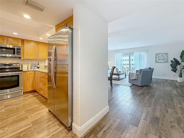 105 4th Ave NE Unit 426, Saint Petersburg, FL 33701 - kitchen featuring stainless steel appliances, light wood-style floors, open floor plan, light brown cabinetry, and light countertops