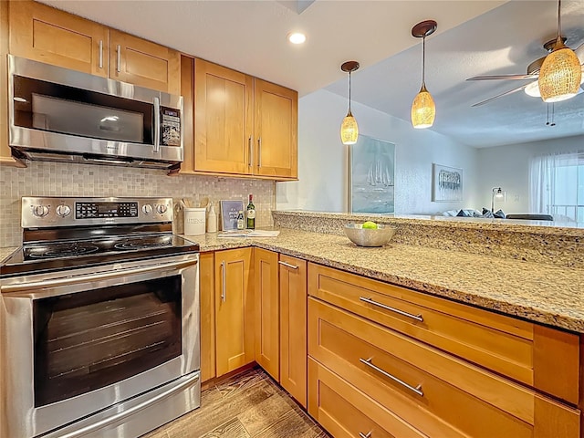 105 4th Ave NE Unit 426, Saint Petersburg, FL 33701 - kitchen with stainless steel appliances, light wood-type flooring, ceiling fan, backsplash, and light stone counters
