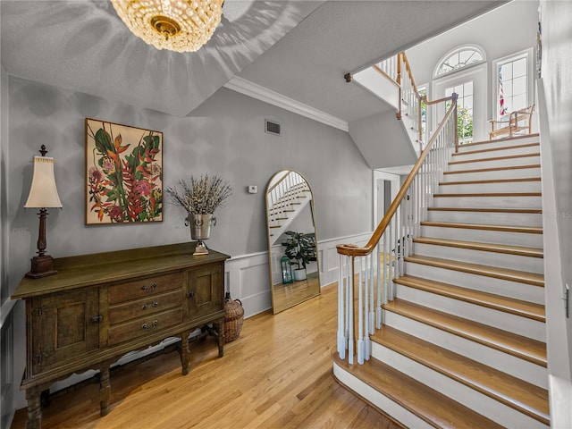 4611 Ackerly Way, Brandon, FL 33511 - staircase featuring ornamental molding, wood finished floors, a chandelier, and a wainscoted wall