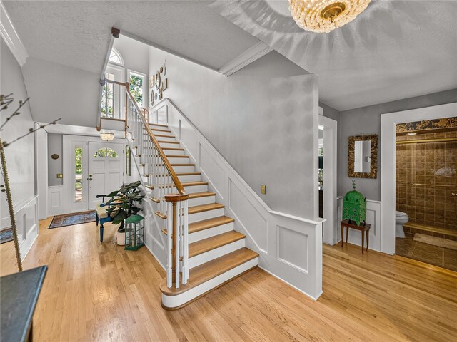 4611 Ackerly Way, Brandon, FL 33511 - foyer entrance with stairway, a decorative wall, light wood finished floors, a chandelier, and a textured ceiling