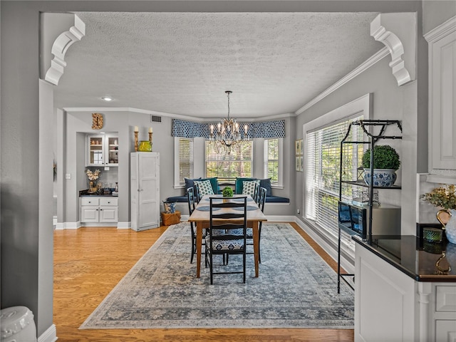 4611 Ackerly Way, Brandon, FL 33511 - dining area with light wood finished floors, a textured ceiling, ornamental molding, and a chandelier
