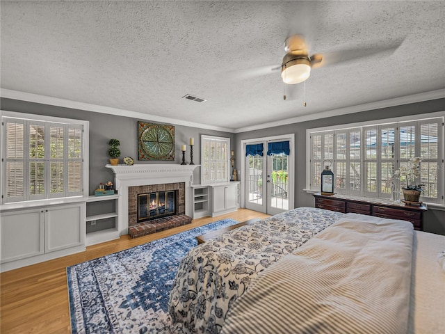 4611 Ackerly Way, Brandon, FL 33511 - bedroom featuring access to outside, light wood-style flooring, ornamental molding, a textured ceiling, and a fireplace