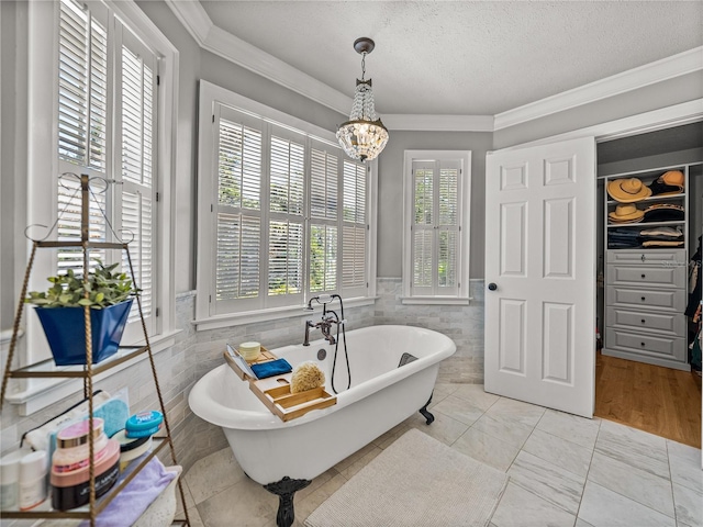 4611 Ackerly Way, Brandon, FL 33511 - bathroom featuring tile walls, a chandelier, a freestanding tub, crown molding, and a textured ceiling