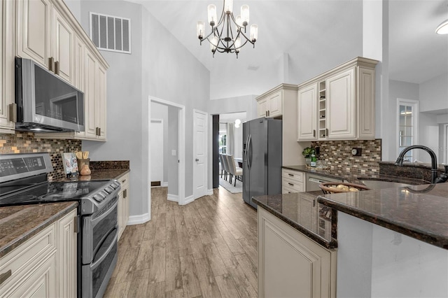 10421 Mesa Ln, Clermont, FL 34711 - kitchen featuring stainless steel appliances, a sink, cream cabinets, baseboards, and a chandelier
