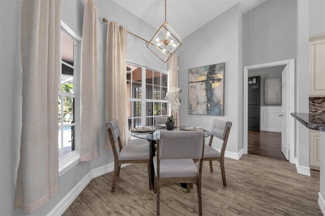 10421 Mesa Ln, Clermont, FL 34711 - dining area featuring a chandelier, high vaulted ceiling, healthy amount of natural light, and wood finished floors