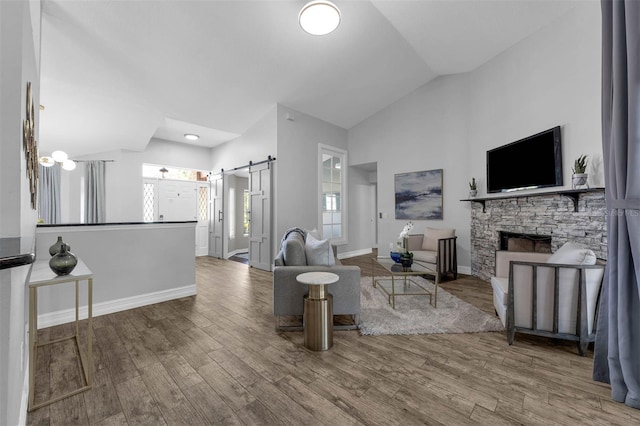 10421 Mesa Ln, Clermont, FL 34711 - living room with a barn door, lofted ceiling, wood finished floors, a stone fireplace, and baseboards