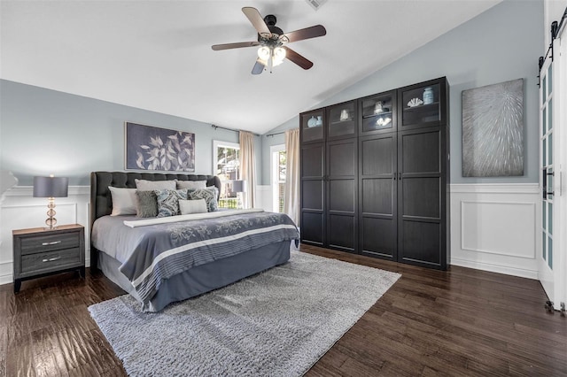 10421 Mesa Ln, Clermont, FL 34711 - bedroom featuring a decorative wall, a barn door, lofted ceiling, dark wood-type flooring, and wainscoting