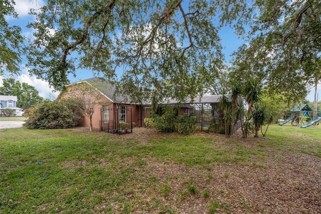 10421 Mesa Ln, Clermont, FL 34711 - view of green lawn with a playground and a lanai