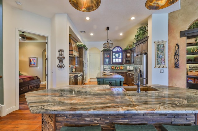 5417 Tybee Island Dr, Apollo Beach, FL 33572 - kitchen featuring arched walkways, freestanding refrigerator, wood finished floors, a center island, and decorative backsplash