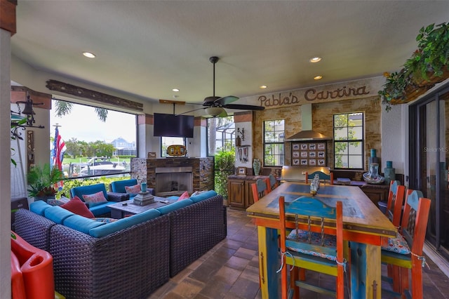 5417 Tybee Island Dr, Apollo Beach, FL 33572 - dining space with a ceiling fan, an outdoor stone fireplace, recessed lighting, and dark stone finish floors