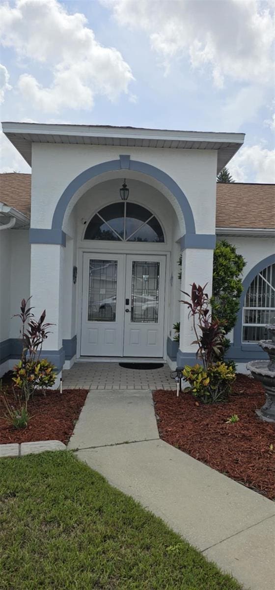 4500 Onorio St, New Port Richey, FL 34653 - property entrance featuring french doors, stucco siding, and roof with shingles