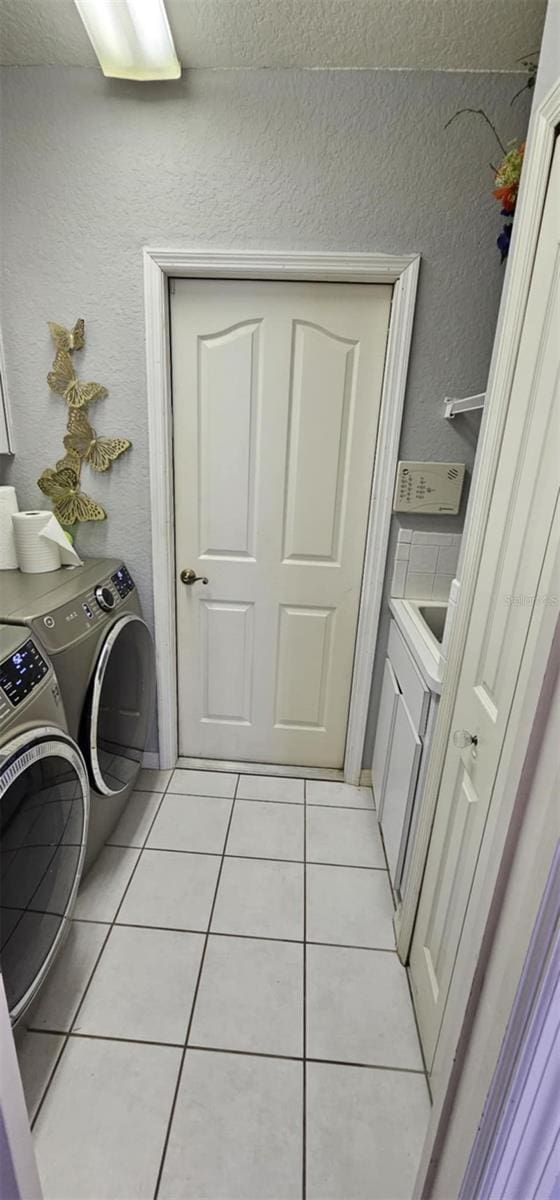4500 Onorio St, New Port Richey, FL 34653 - laundry area featuring washing machine and clothes dryer, light tile patterned floors, a textured wall, and a textured ceiling