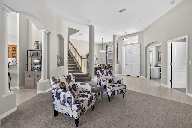 111 Falling Water Dr, Brandon, FL 33511 - living room featuring light tile patterned floors, light colored carpet, arched walkways, stairway, and ornate columns
