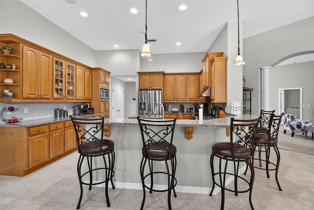 111 Falling Water Dr, Brandon, FL 33511 - kitchen featuring appliances with stainless steel finishes, a peninsula, decorative columns, a kitchen breakfast bar, and light stone countertops