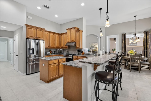 111 Falling Water Dr, Brandon, FL 33511 - kitchen featuring appliances with stainless steel finishes, under cabinet range hood, a center island, dark stone countertops, and brown cabinetry