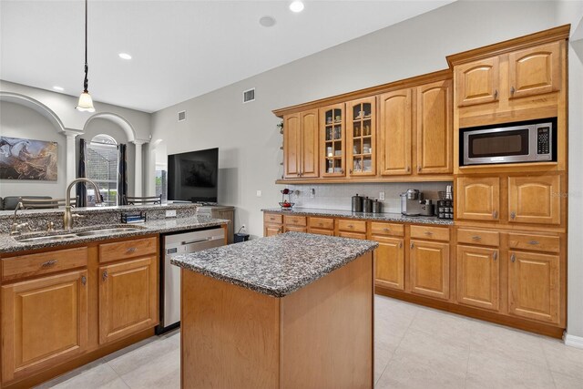 111 Falling Water Dr, Brandon, FL 33511 - kitchen featuring stainless steel appliances, ornate columns, dark stone counters, open floor plan, and glass insert cabinets
